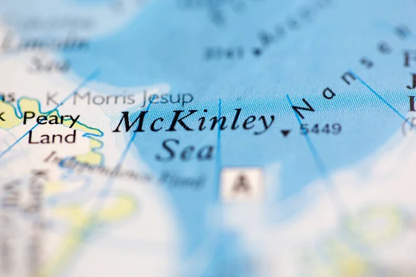 Shallow depth of field focus on geographical map location of McKinley Sea off coast of Greenland on atlas