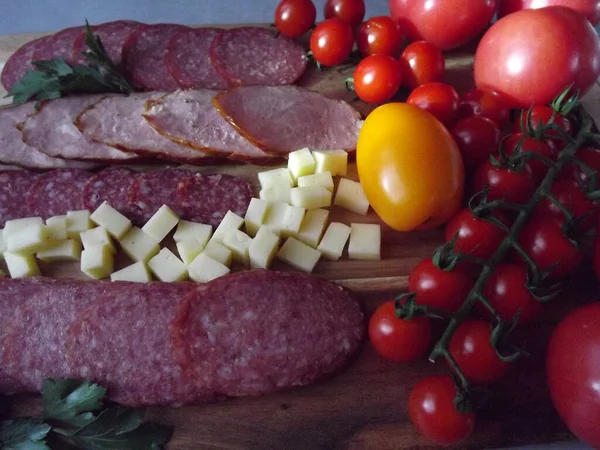 Slicing smoked sausage of four varieties with cheese and red and yellow tomatoes and cherry tomatoes — Stock Photo, Image