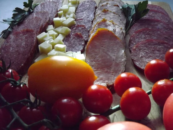 Fatias de salsicha defumada de quatro variedades com queijo e tomates vermelhos e amarelos e tomates cereja — Fotografia de Stock