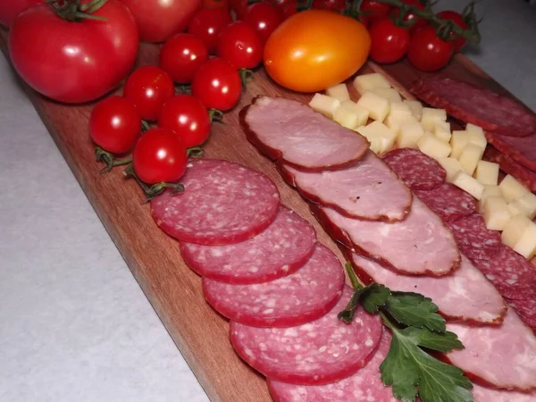 Fatias de salsicha defumada de quatro variedades com queijo e tomates vermelhos e amarelos e tomates cereja — Fotografia de Stock