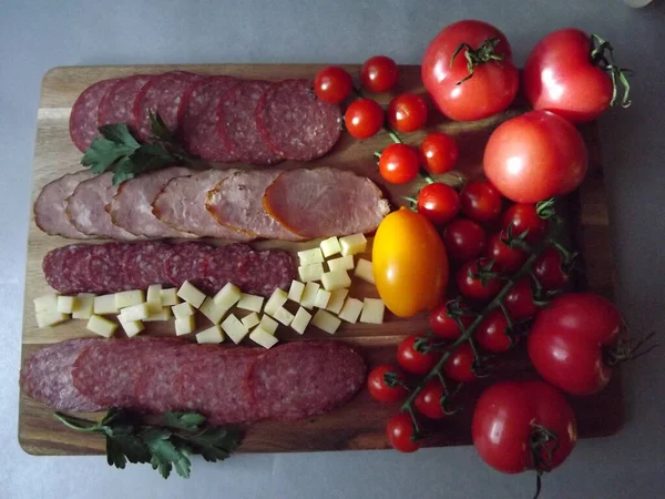 Fatias de salsicha defumada de quatro variedades com queijo e tomates vermelhos e amarelos e tomates cereja — Fotografia de Stock