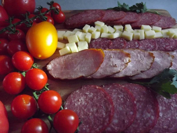 Fatias de salsicha defumada de quatro variedades com queijo e tomates vermelhos e amarelos e tomates cereja — Fotografia de Stock