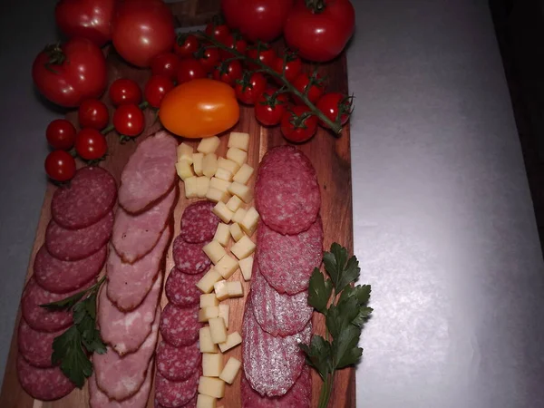 Нарізати копчену ковбасу чотирьох сортів з сиром, червоними та жовтими помідорами та вишневими помідорами — стокове фото