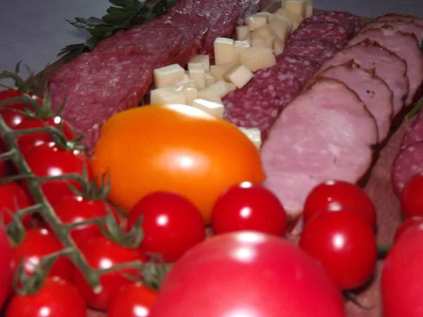 Slicing smoked sausage of four varieties with cheese and red and yellow tomatoes and cherry tomatoes — Stock Photo, Image