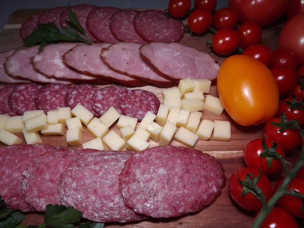 Slicing smoked sausage of four varieties with cheese and red and yellow tomatoes and cherry tomatoes — Stock Photo, Image