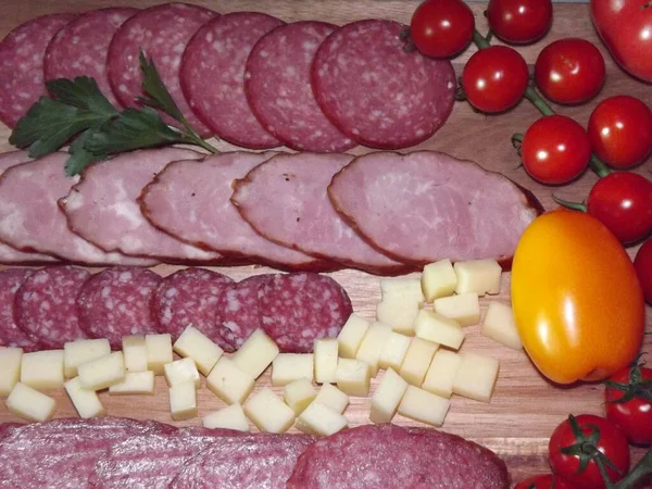 Fatias de salsicha defumada de quatro variedades com queijo e tomates vermelhos e amarelos e tomates cereja — Fotografia de Stock