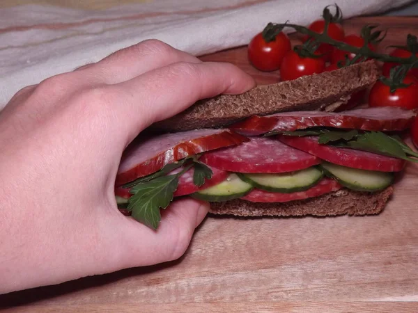 Farklı türde sosis ve sebzeli bir sandviçi tutarken. — Stok fotoğraf