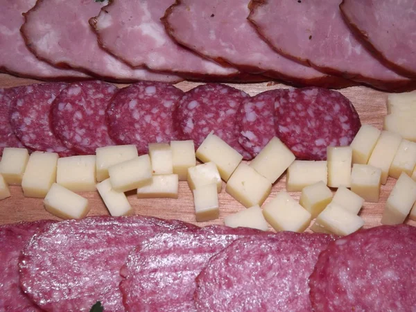 Slicing smoked sausage of four varieties with cheese and red and yellow tomatoes and cherry tomatoes — Stock Photo, Image