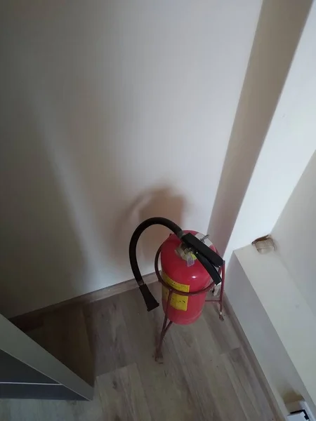 Red fire extinguisher on stand in office space — Stock Photo, Image