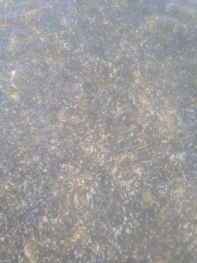 Küçük çakıl taşları ve su ile kıyı şeridi