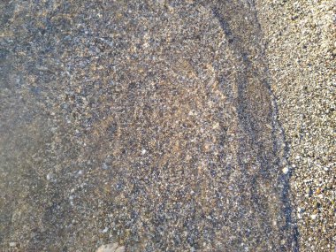 Küçük çakıl taşları ve su ile kıyı şeridi