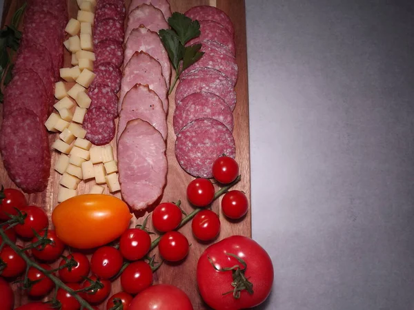 Fatias de salsicha defumada de quatro variedades com queijo e tomates vermelhos e amarelos e tomates cereja — Fotografia de Stock