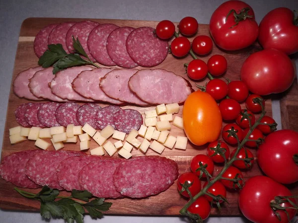 Fatias de salsicha defumada de quatro variedades com queijo e tomates vermelhos e amarelos e tomates cereja — Fotografia de Stock