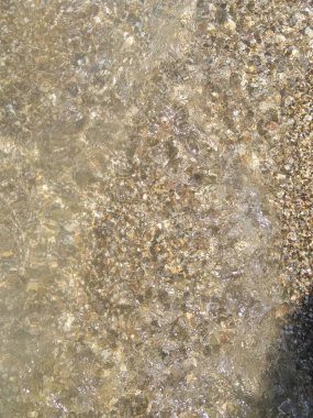 Küçük çakıl taşları ve su ile kıyı şeridi