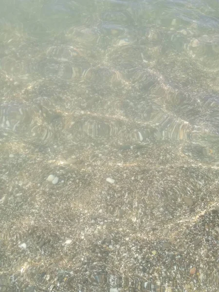 Küçük çakıl taşları ve su ile kıyı şeridi