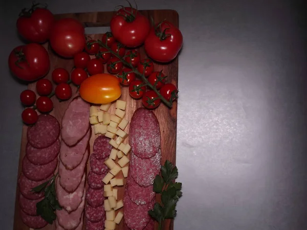 Fatias de salsicha defumada de quatro variedades com queijo e tomates vermelhos e amarelos e tomates cereja — Fotografia de Stock