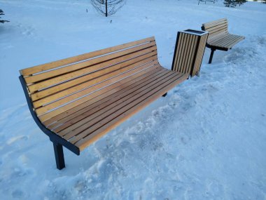 Kışın şehir parkında ahşap bank ve çöp kutusu