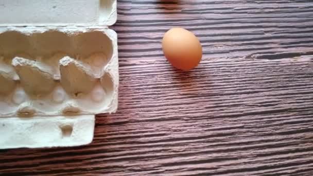 女性の手は卵の箱からベージュの卵を取り — ストック動画