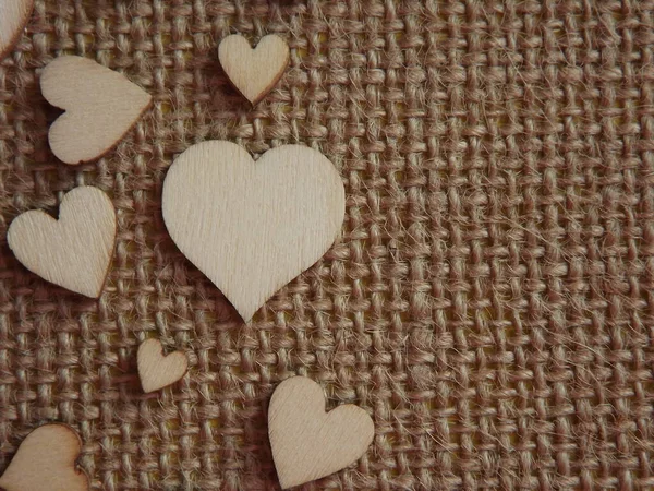 Corazones de madera de diferentes tamaños en tela de yute como tarjeta de felicitación del día de San Valentín — Foto de Stock