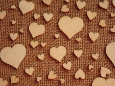 Sevgililer günü tebrik kartı olarak jüt kumaşında farklı boyutlarda tahta kalpler.