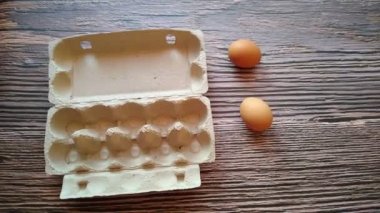 Bir kadının eli yumurta kutusundan bej bir yumurta alır.