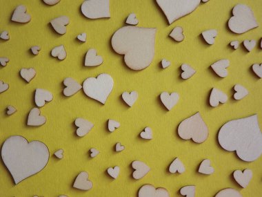 Sarı arka planda farklı boyutlarda tahta kalpler. Sevgililer Günü, bir aşk ilanı