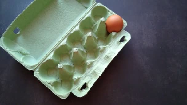 Bir kadının eli yumurta kutusundan bej bir yumurta alır. — Stok video