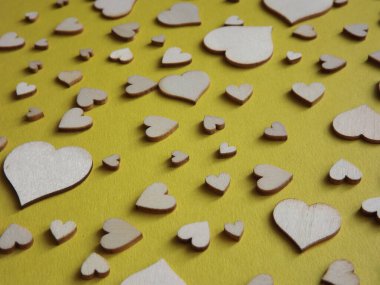 Sarı arka planda farklı boyutlarda tahta kalpler. Sevgililer Günü, bir aşk ilanı