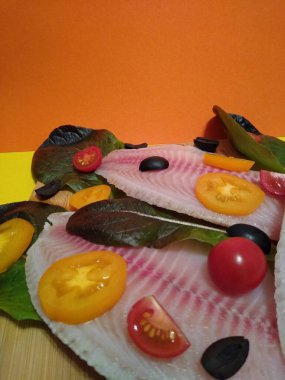 Domatesli, zeytinli ve marullu tilapia balığı filetosu pişirme işlemi