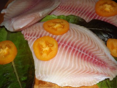 Domatesli, zeytinli ve marullu tilapia balığı filetosu pişirme işlemi