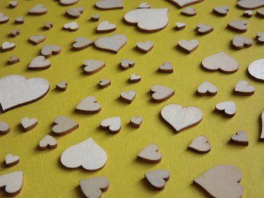 Sarı arka planda farklı boyutlarda tahta kalpler. Sevgililer Günü, bir aşk ilanı