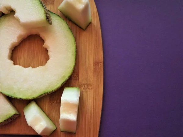 ripe melon cut into slices on a wooden board