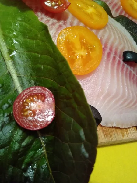 El proceso de cocción del filete de tilapia con tomates, aceitunas y hojas de lechuga — Foto de Stock