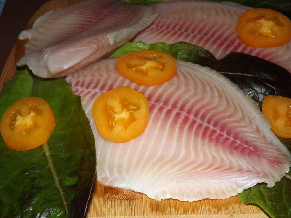 El proceso de cocción del filete de tilapia con tomates, aceitunas y hojas de lechuga — Foto de Stock