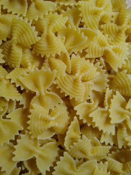 Macarrão na forma de arcos em um recipiente de vidro em um fundo de madeira — Fotografia de Stock