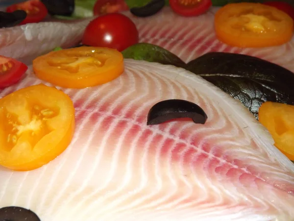 Processen för tillagning av tilapia fiskfilé med tomater, oliver och salladsblad — Stockfoto