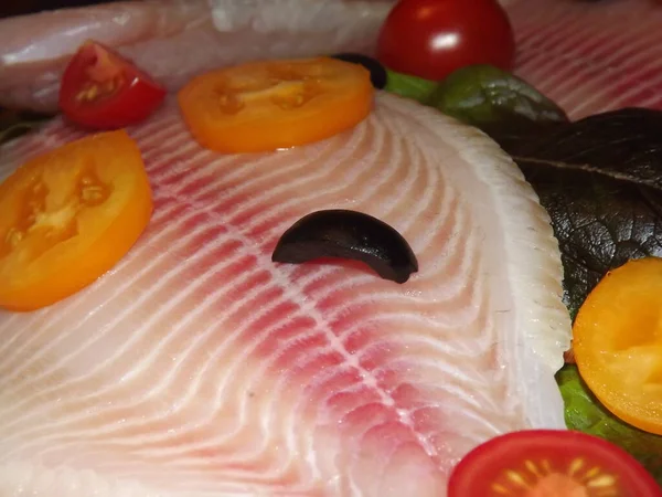 Processen för tillagning av tilapia fiskfilé med tomater, oliver och salladsblad — Stockfoto