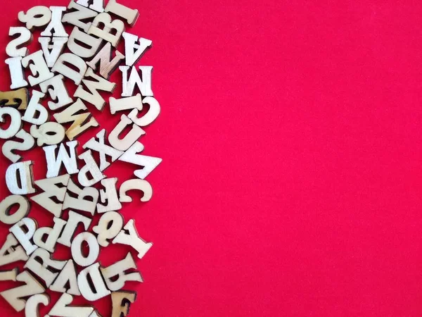 Wooden letters of the alphabet scattered on a red background with space for text — Stock Photo, Image