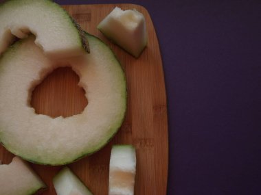 Olgun kavun tahta üzerinde dilimler halinde kesilmiş.