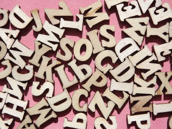 粉红绒面革作为背景的英文字母的木制字母 — 图库照片