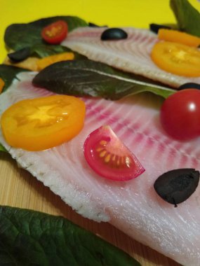 Domatesli, zeytinli ve marullu tilapia balığı filetosu pişirme işlemi