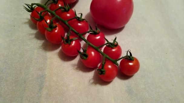 Dos tomates grandes y tomates cherry en las ramas se cierran sobre un fondo beige — Vídeos de Stock