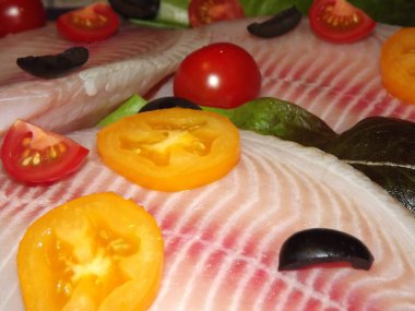 Domatesli, zeytinli ve marullu tilapia balığı filetosu pişirme işlemi