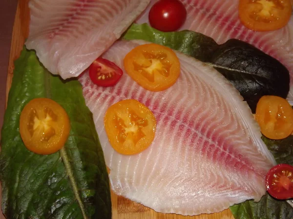 El proceso de cocción del filete de tilapia con tomates, aceitunas y hojas de lechuga — Foto de Stock