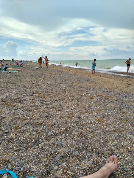 Hommes et femmes se détendre sur la plage par temps nuageux — Photo