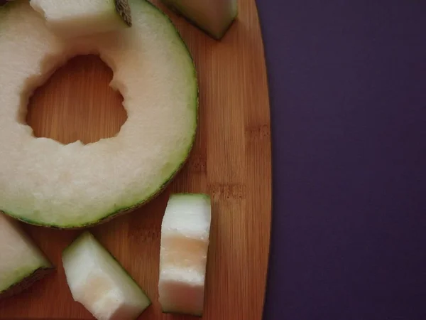 ripe melon cut into slices on a wooden board