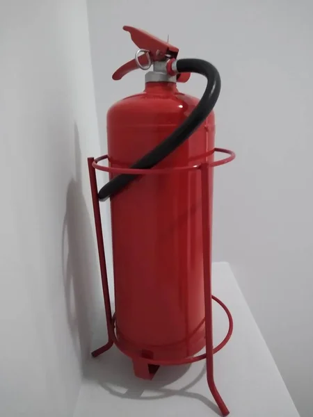 red fire extinguisher in the corner of the office space on a stand
