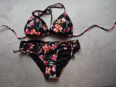 Gri bir arka planda siyah bikini mayo giymiş bir kadının çizimi.