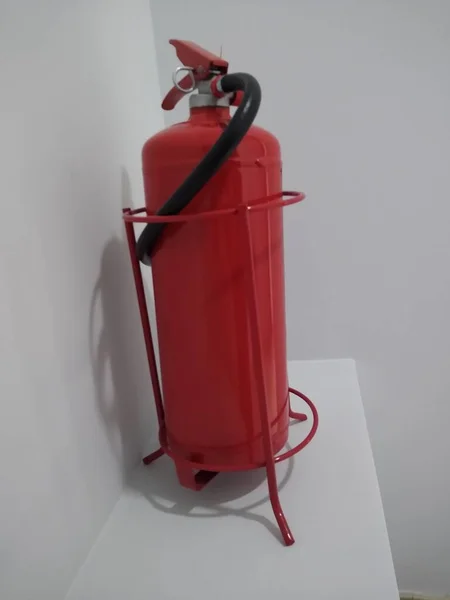 Red fire extinguisher in the corner of the office space on a stand — Stock Photo, Image