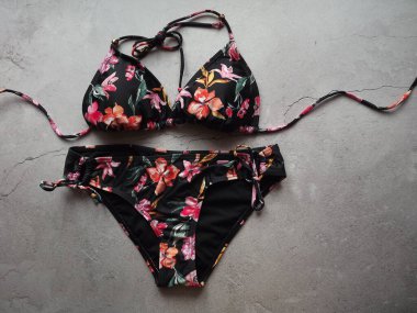 Gri bir arka planda siyah bikini mayo giymiş bir kadının çizimi.